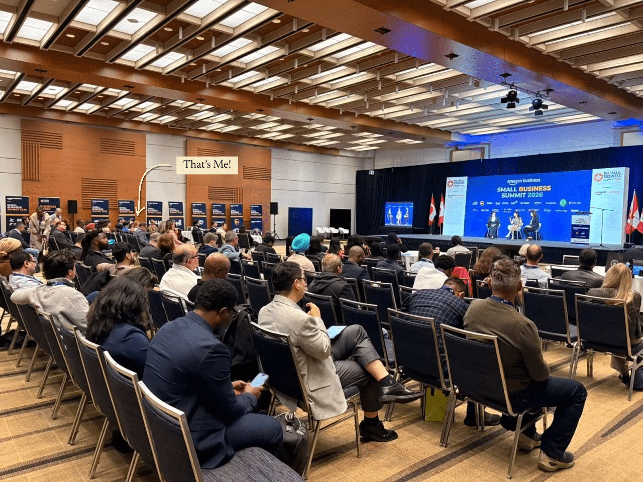 The AI panel on stage at the CanadianSME Small Business Summit in Toronto, with an arrow marking Hayley in the audience